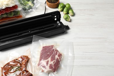 Vacuum packing sealer and different food products on white wooden table. Space for text