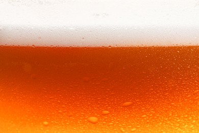 Glass of tasty cold beer with foam and condensation drops, closeup