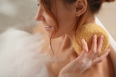 Woman rubbing neck with sponge while taking bath, closeup