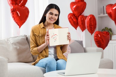 Photo of Valentine's day celebration in long distance relationship. Woman having video chat with her boyfriend via laptop at home