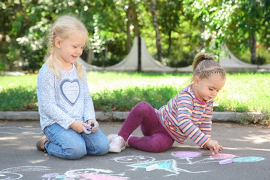 Little children drawing with colorful chalk on asphalt