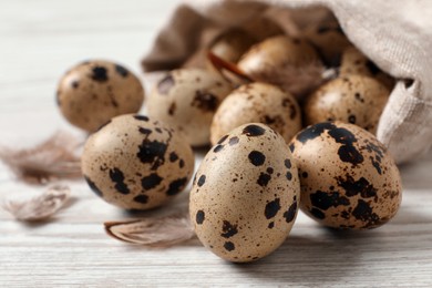 Photo of Fresh quail eggs and feathers on white wooden table, closeup