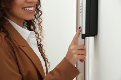 African-American woman pushing intercom button in entryway, closeup