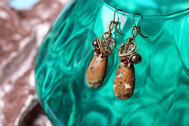Beautiful pair of metal earrings with jasper gemstones on glass stand