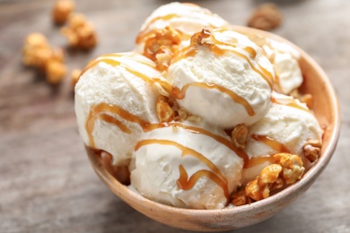 Tasty ice cream with caramel sauce and popcorn in bowl on table, closeup