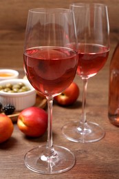 Photo of Delicious rose wine and snacks on wooden table