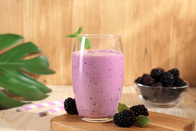 Delicious blackberry smoothie in glass and berries on wooden table