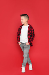 Full length portrait of cute little boy on red background