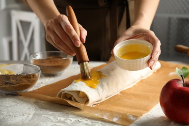 Woman making delicious apple strudel at table, closeup