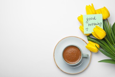 Cup of aromatic coffee, beautiful yellow tulips and Good Morning note on white background, flat lay. Space for text