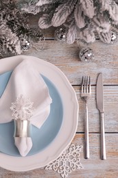 Photo of Festive place setting with beautiful dishware, cutlery and fabric napkin for Christmas dinner on light blue wooden table, flat lay