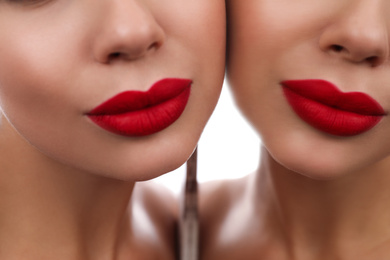 Beautiful woman with red lipstick near mirror, closeup