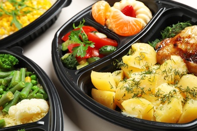 Lunchboxes with different meals on white table, closeup. Healthy food delivery