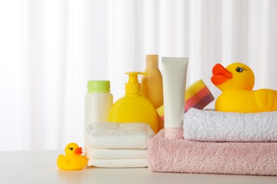 Photo of Towels, rubber ducks and baby care products on white table indoors