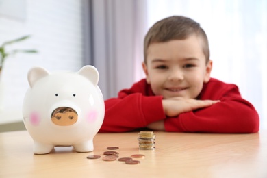 Little boy with piggy bank and money at home, closeup