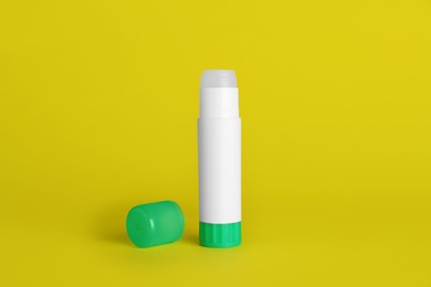 Photo of Blank glue stick and cap on yellow background