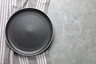 New dark plate and tablecloth on light grey marble table, top view. Space for text
