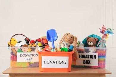 Donation boxes with different child toys on wooden table