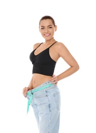 Slim woman in oversized jeans with measuring tape on white background. Weight loss