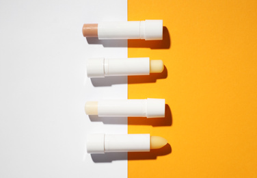 Hygienic lipsticks on color background, flat lay