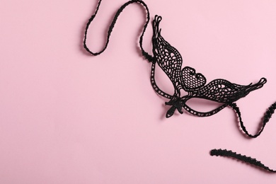 Black lace mask for sexual role play on pink background, top view with space for text