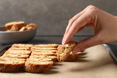 Photo of Woman taking traditional Italian almond biscuit (Cantucci) from baking sheet, closeup