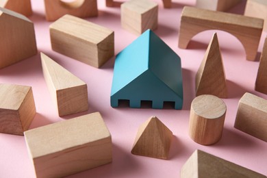 One turquoise toy building block among others on pink background. Diversity concept