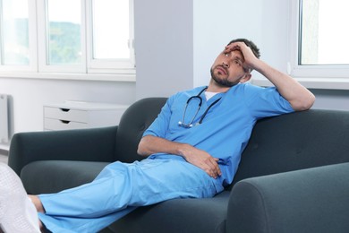 Exhausted doctor resting on sofa in hospital