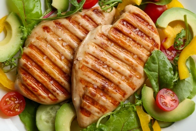 Tasty grilled chicken fillets with vegetables on plate, closeup