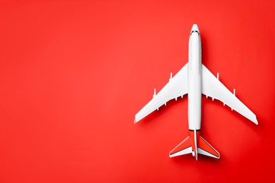 Top view of toy plane on red background, space for text. Logistics and wholesale concept