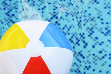 Inflatable beach ball floating in swimming pool, above view. Space for text