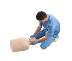 Doctor in uniform practicing first aid on mannequin against white background