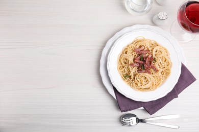 Delicious Carbonara pasta served on white wooden table, flat lay. Space for text