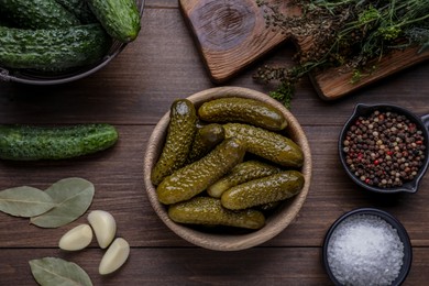 Photo of Bowl of pickled cucumbers and ingredients on wooden table, flat lay