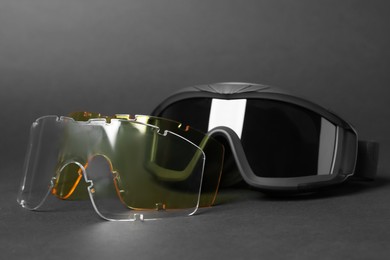 Photo of Tactical glasses and different lenses on black background, closeup. Military training equipment