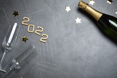 Happy New Year 2022! Flat lay composition with bottle of sparkling wine on grey table, space for text