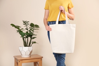 Woman with eco bag near green plant on color background. Mock up for design