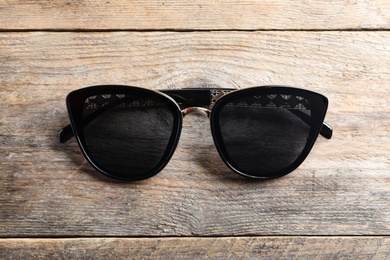 Stylish sunglasses on wooden background, top view