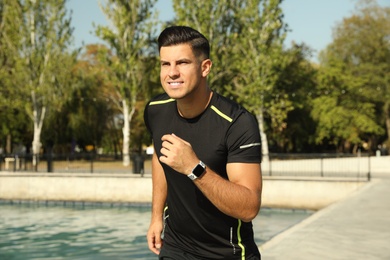 Man wearing modern smart watch during training near river