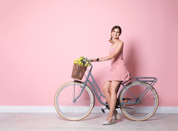 Portrait of beautiful woman with bicycle near color wall