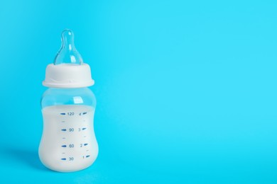 Photo of One feeding bottle with milk on light blue background. Space for text