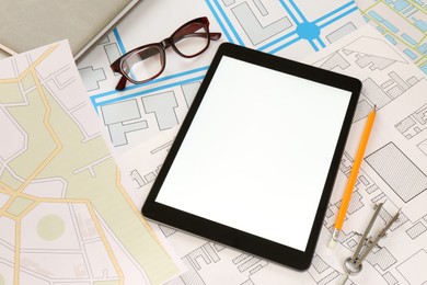 Office stationery, eyeglasses and tablet on cadastral maps of territory with buildings