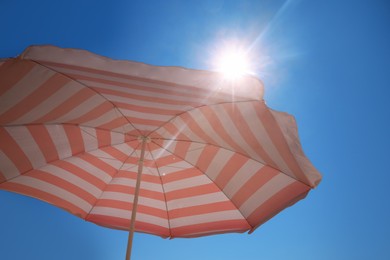Red and white striped beach umbrella against blue sky on sunny day