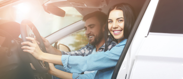Image of Happy woman and her boyfriend sitting in modern auto outdoors on sunny day. Banner design