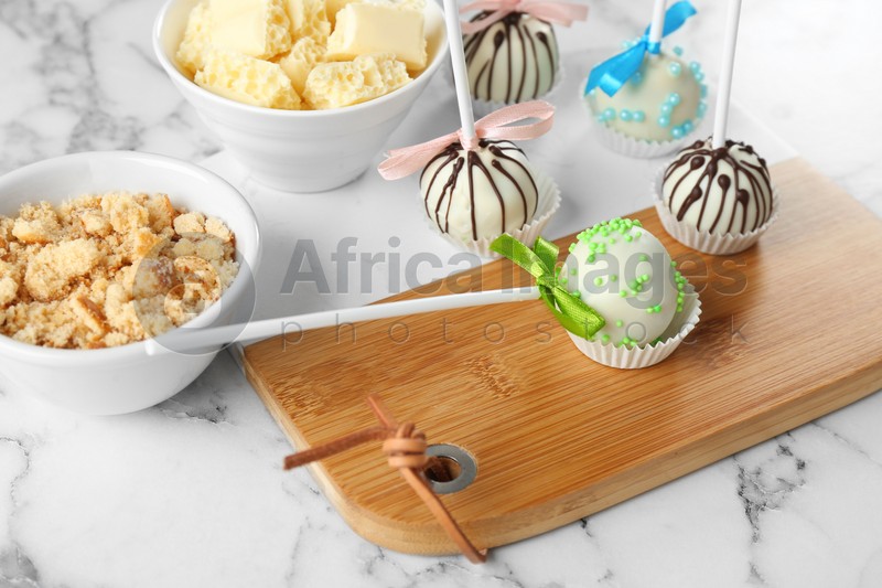 Tasty colorful cake pops on white marble table