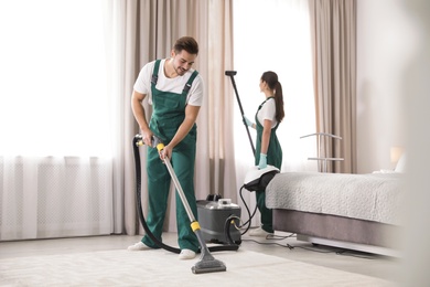 Team of janitors cleaning bedroom with professional equipment
