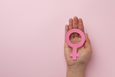 Photo of Woman holding female gender sign on pink background, top view. Space for text