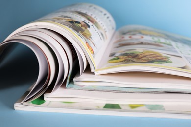 Stack of magazines on light blue background, closeup