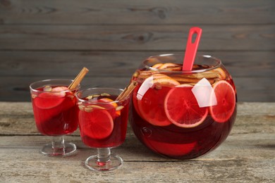 Glasses and bowl with aromatic punch drink on wooden table
