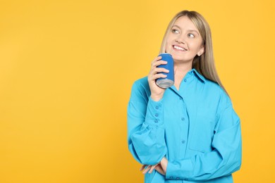 Photo of Beautiful happy woman holding beverage can on yellow background. Space for text